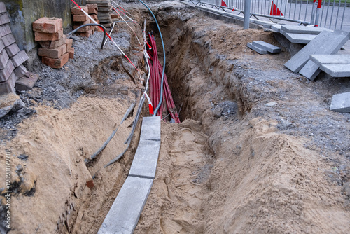 Konstfotografi Excavation trench with red utility cables and bricks