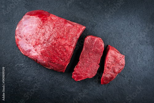 Tableau sur toile Boneless venison haunch - top round steak raw offered as top view on a slate pla