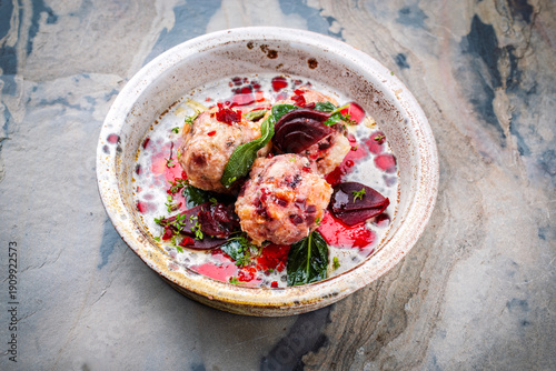 Homemade vegan bread knodel dumpling with beetroot and fresh buttered sage served as close-up on a design plate