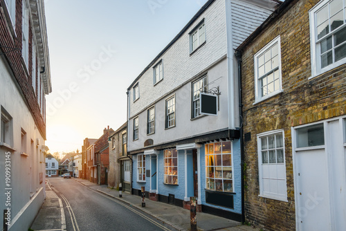 Traditional brick buildings and shops along a narrow street in a city centre at sunset in spring