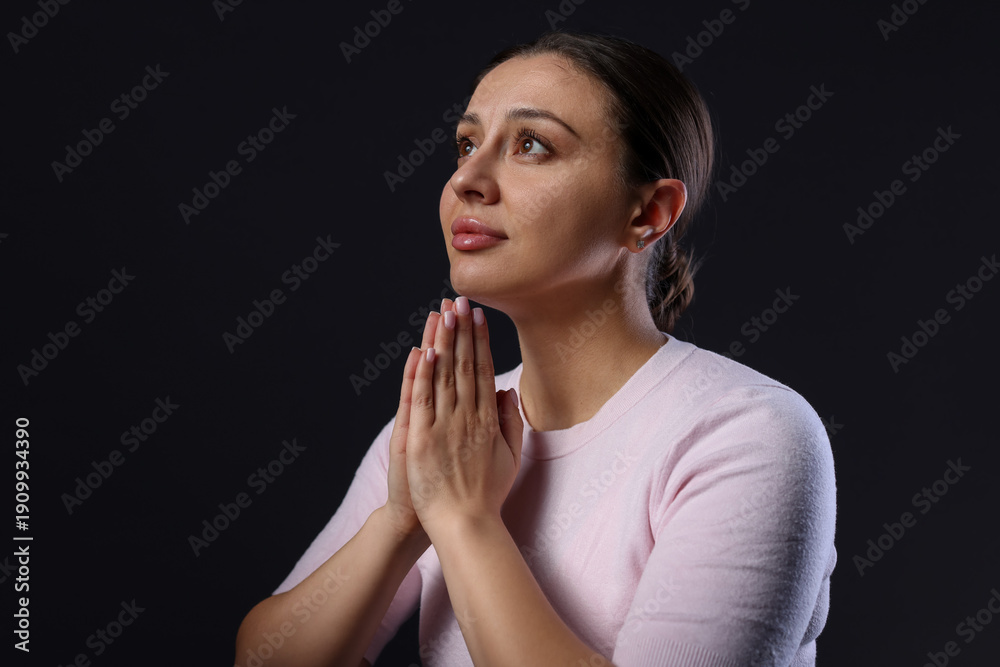 © New Africa - Religion. Christian woman praying on black background