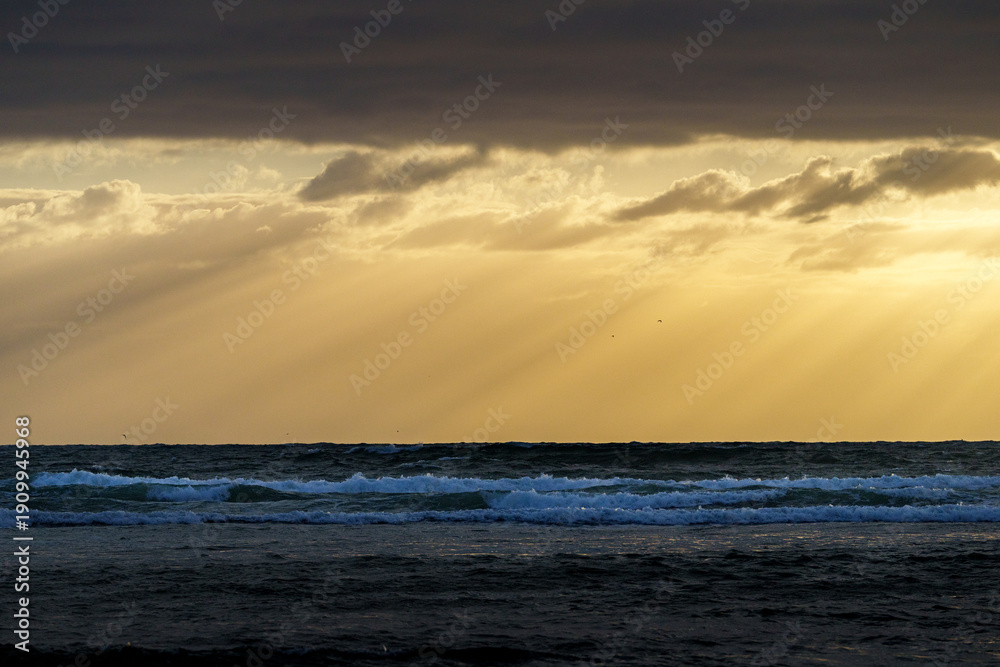 Obraz premium Dark cloudy sky and sea separated by golden hour moody sky