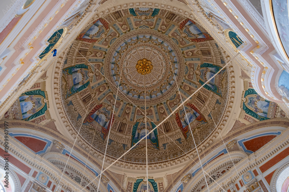 Naklejka premium Looking up at the richly decorated dome inside Ortakoy Mosque (Buyuk Mecidiye Camii) in Istanbul, Turkey, featuring Ottoman-Baroque stucco, painted panels and gilded detail