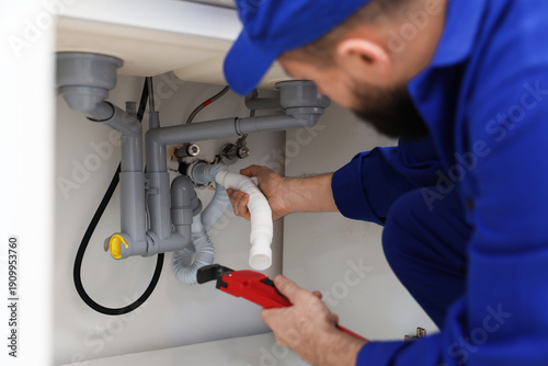 Canvas Print Plumber with wrench fixing piping system indoors, closeup