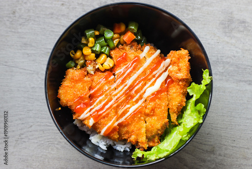 Crispy Japanese Chicken Katsu Donburi with Mayonnaise and Spicy Chili Sauce on White Rice, Fusion Fried Breaded Chicken Rice Bowl with Sautéed Vegetables in Black Bowl, Top View Food Photography