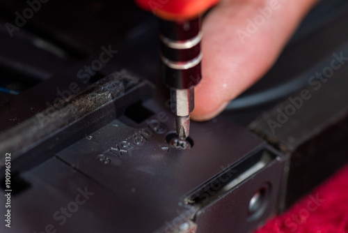 Quadro em tela Closeup of someone using a screwdriver to tighten a screw in dark plastic