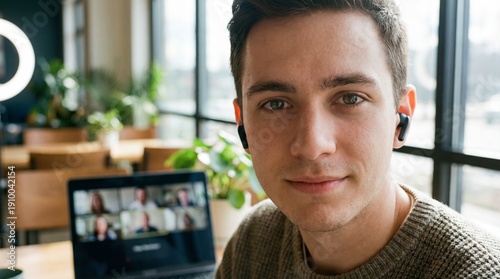 Young Man Attending Virtual Meeting on Laptop, Close-Up Portrait in Cozy Cafe with Wireless Earbuds, Working from Home, Remote Work, Online Conference, and Digital Collaboration Concept