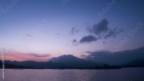 Serene sunset colors paint the sky, the mountains mirrored in the tranquil lake waters, creating a peaceful, dreamlike landscape.