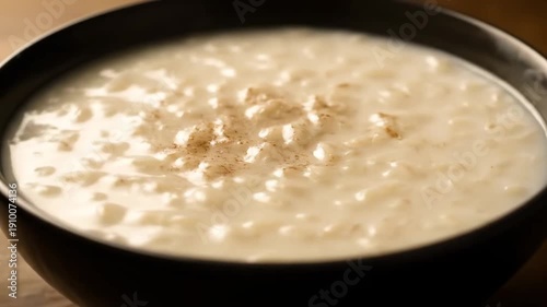 Homemade Creamy Rice Pudding (Arroz con Leche) Served in a Dark Bowl, Garnished with Cinnamon Powder. Close-up of Traditional Sweet Dessert.