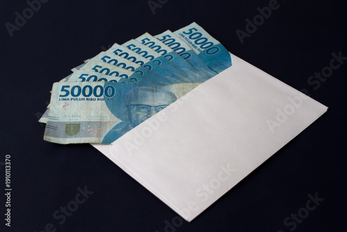 High-angle shot of Rupiah banknotes in an envelope representing the distribution of 