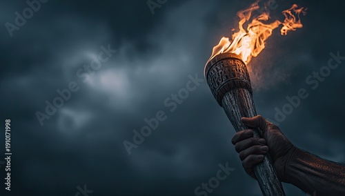 A hand firmly grips a wooden torch, its flames blazing against a dramatic, stormy sky