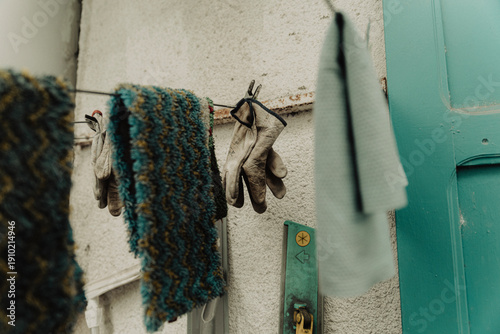 Gants de travail suspendus sur un fil à linge devant une façade turquoise