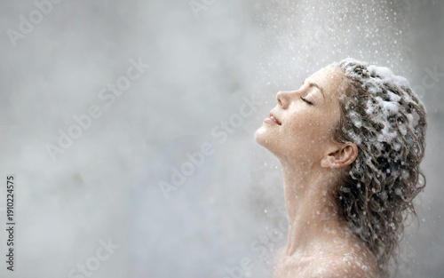 Young woman washing her hair with shampoo in the shower with white steam around her