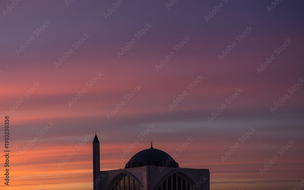 Obraz premium A serene mosque silhouette against a vibrant purple and orange sunset sky
