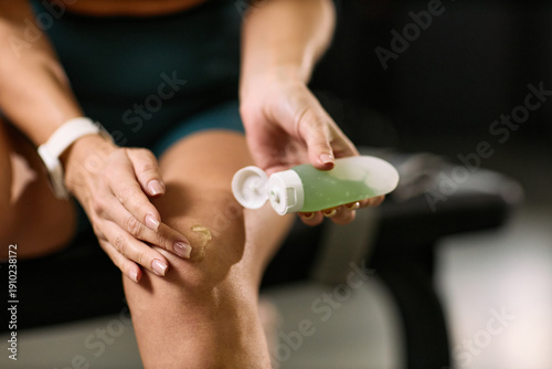 Fotografie Caucasian middle aged woman applying topical gel to knee during physical therapy