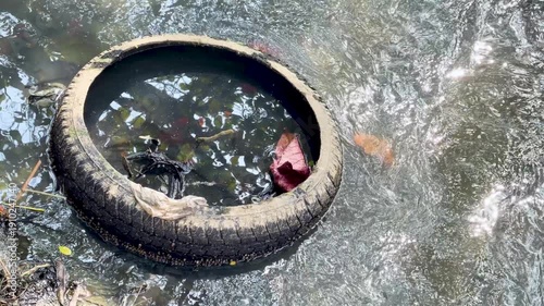 Discarded Rubber Car Tire Floating in Polluted Water in Thailand