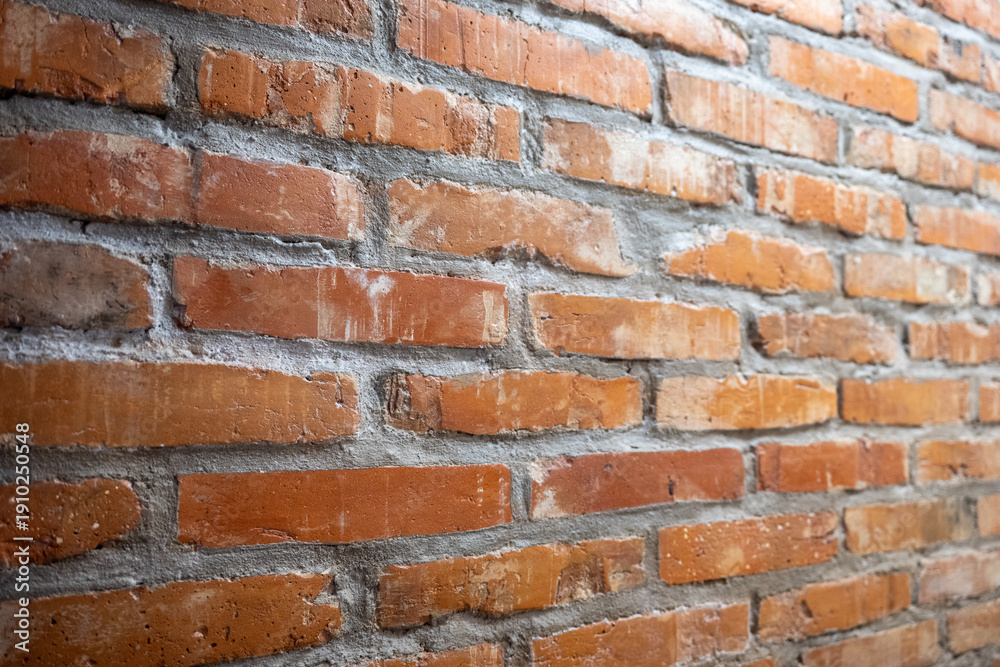 Obraz premium Close up of red brick wall with visible mortar joints and rough masonry texture, angled perspective construction background.