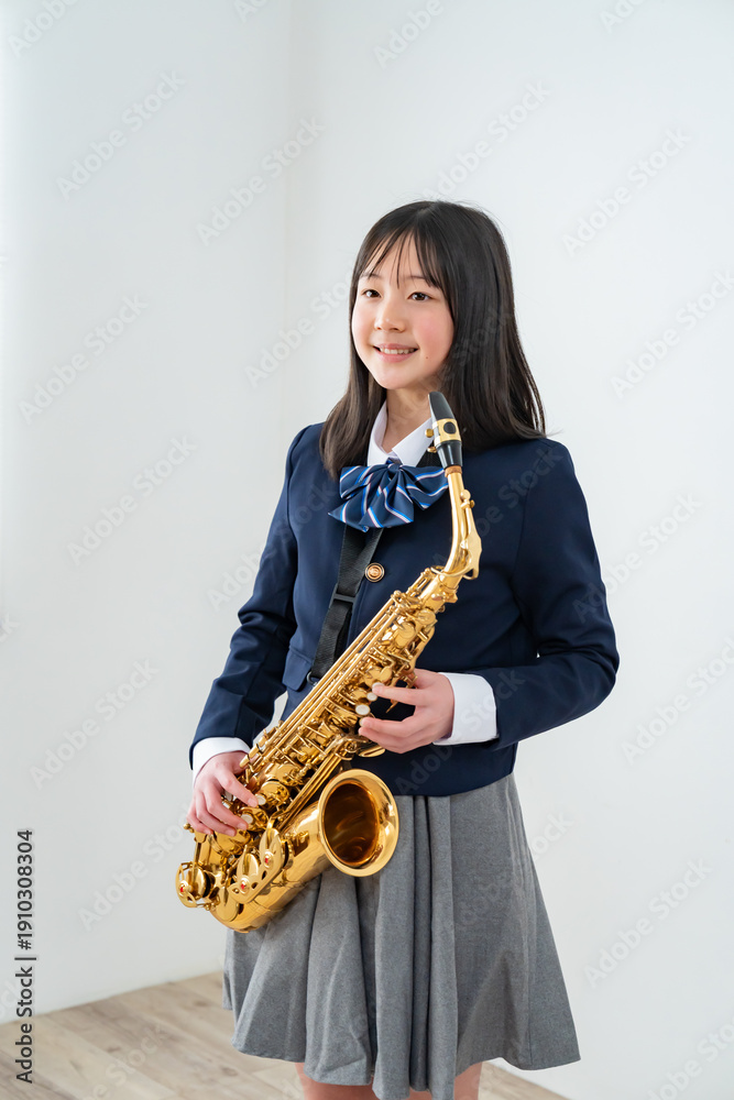Naklejka premium アルトサックスを持って笑顔の制服姿の日本人少女