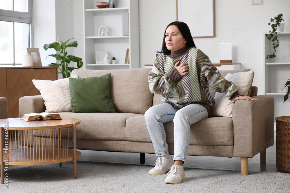 Obraz premium Young woman having heart attack on sofa at home