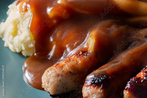 Fotografie Bangers and mash with pork sausage and butter mashed potato covered in onion gravy on a green plate