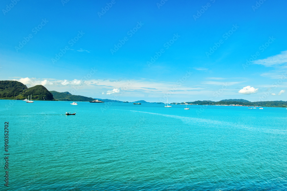 Fototapeta premium A beautiful view of Langkawi island against a beautiful blue sky with some boats in the distance on the horizon. Tropical scenery. located at Kedah, Malaysia - September 25 2024: