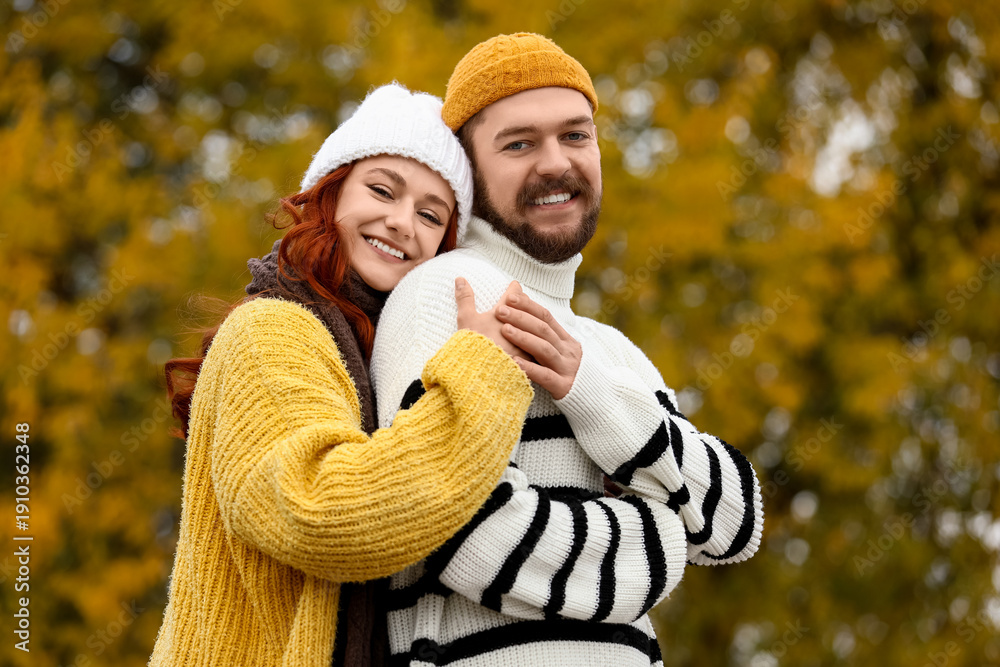 Fototapeta premium Cute young couple in warm sweaters hugging at autumn park