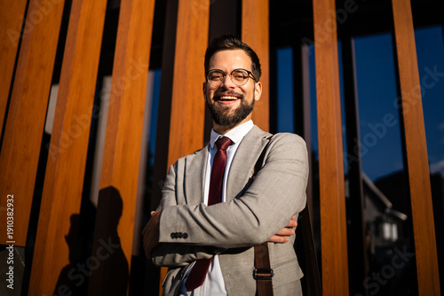 Fotografía Smiling businessman posing with crossed arms in front of modern building
