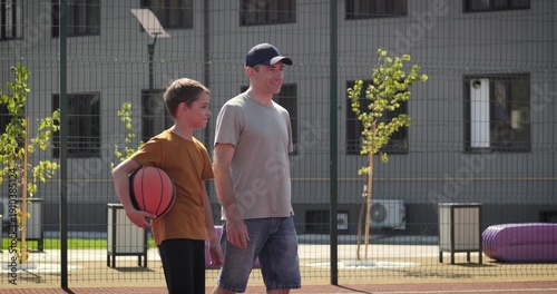 Konstfotografi Father accompanies son on outdoor basketball court in city area
