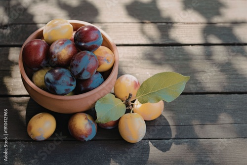 Fresh plums in terracotta bowl on wooden table