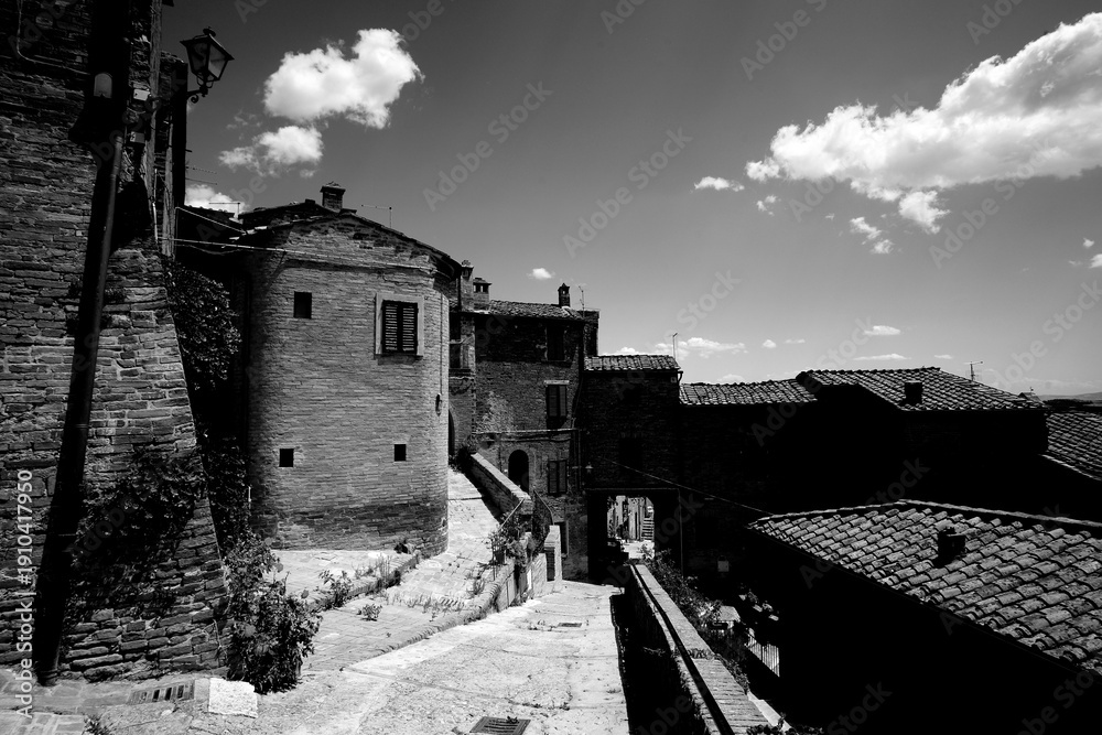 Fototapeta premium Borghi toscani in bianco e nero. L'architettura medievale dei borghi toscani, caratterizzata da pietra, cotto, riflette il periodo comunale con cinte murarie, torri, vicoli stretti e piazze. Italia. 