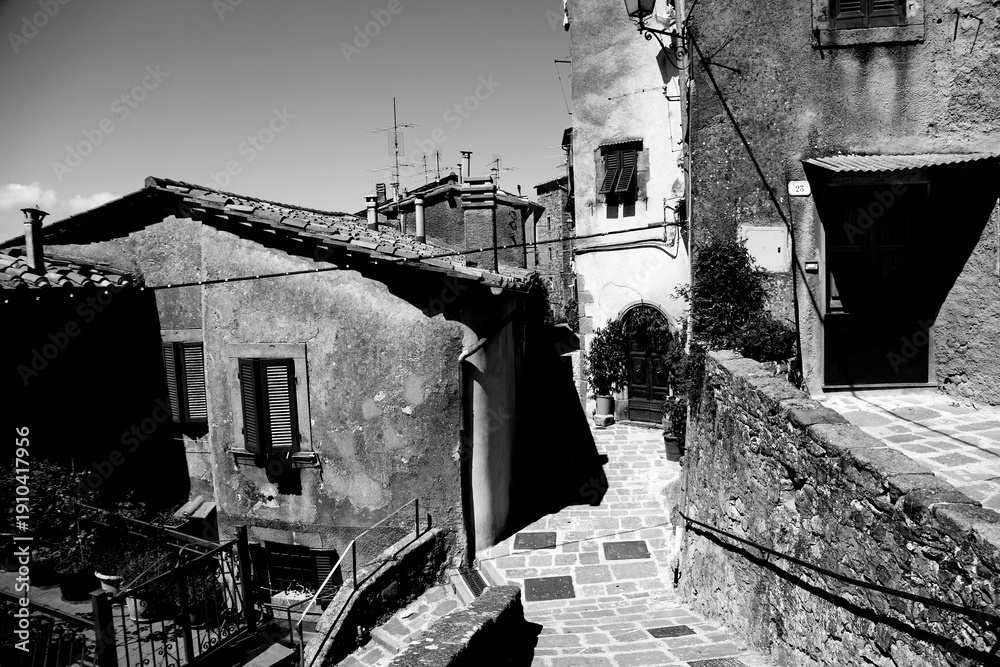 Fototapeta premium Borghi toscani in bianco e nero. L'architettura medievale dei borghi toscani, caratterizzata da pietra, cotto, riflette il periodo comunale con cinte murarie, torri, vicoli stretti e piazze. Italia. 
