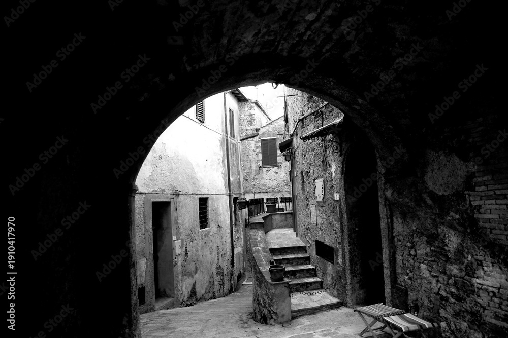 Fototapeta premium Borghi toscani in bianco e nero. L'architettura medievale dei borghi toscani, caratterizzata da pietra, cotto, riflette il periodo comunale con cinte murarie, torri, vicoli stretti e piazze. Italia. 