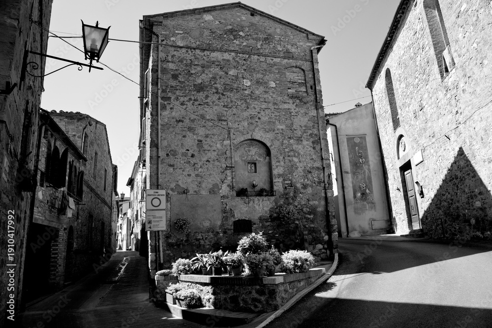 Fototapeta premium Borghi toscani in bianco e nero. L'architettura medievale dei borghi toscani, caratterizzata da pietra, cotto, riflette il periodo comunale con cinte murarie, torri, vicoli stretti e piazze. Italia. 