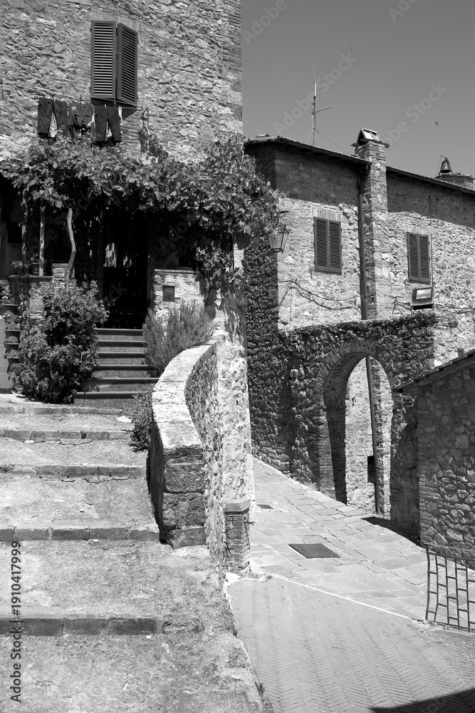 Fototapeta premium Borghi toscani in bianco e nero. L'architettura medievale dei borghi toscani, caratterizzata da pietra, cotto, riflette il periodo comunale con cinte murarie, torri, vicoli stretti e piazze. Italia. 