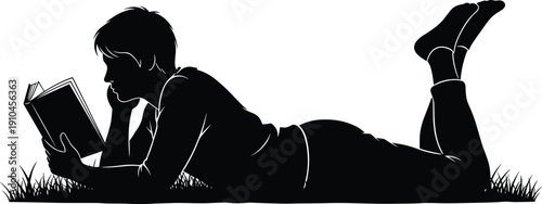 Silhouette of a person lying on grass reading a book, with a focus on the relaxed posture and outdoor setting