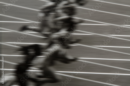 Vászonkép High-energy action shot of sprinters exploding from starting blocks on track
