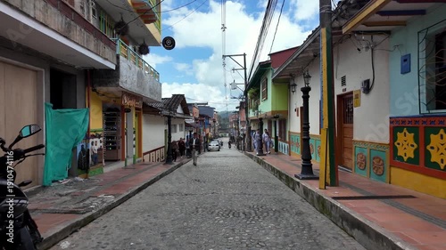 POV Moving Downhill View Along Bustling Commercial Street Lined With Colorful Zócalo Buildings in Guatape, Colombia.