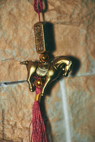 Decoration in the form of a golden horse on the background of a stone wall for the year of the Horse