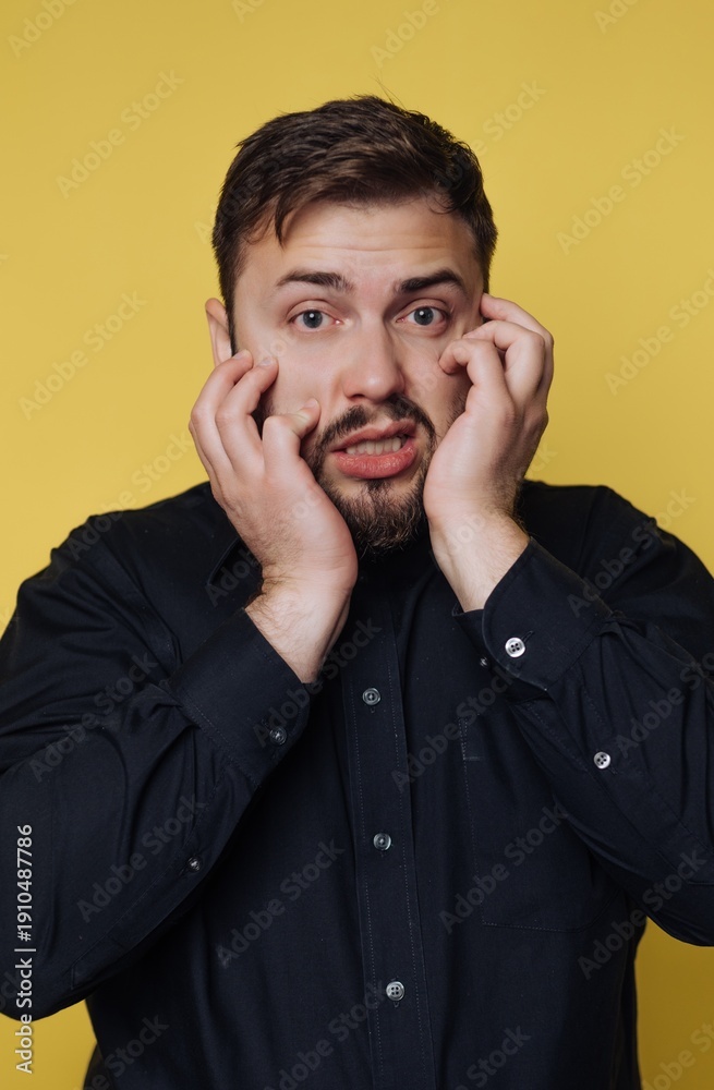 © bodnarphoto - Surprised man expresses shock against bright yellow backdrop during a candid moment in a lively studio setting