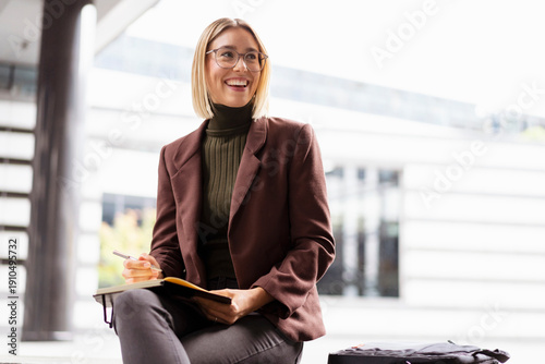 Smiling young businesswoman with notebook in the city