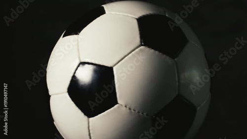 Seamless loop of a spinning soccer ball isolated on a dark background close up