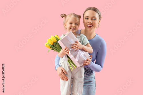 Little girl with her mother, tulips and gift box on pink background. International Women's Day