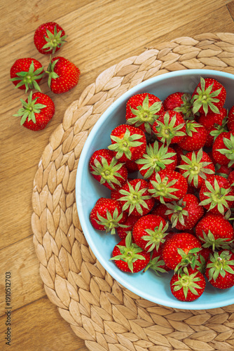 Fresh strawberries in a blue bowl on a wooden table