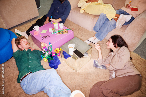 Wallpaper Mural High angle view of male and female entrepreneurs lying down on carpet during break time in office Torontodigital.ca