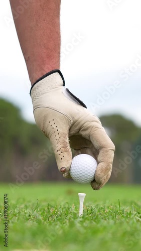 A man is holding a golf ball and a golf club, preparing to hit the ball. Concept of focus and determination, as the man is getting ready to make a shot on the golf course