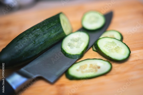 Wallpaper Mural Chef's knife next to sliced cucumber rounds on a bamboo cutting board. Fresh food preparation close-up. Torontodigital.ca