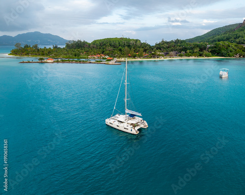 Wallpaper Mural Aerial view of a pristine catamaran slicing through the turquoise waters towards a lush island paradise under a serene sky, Mont Fleuri, Seychelles. Torontodigital.ca