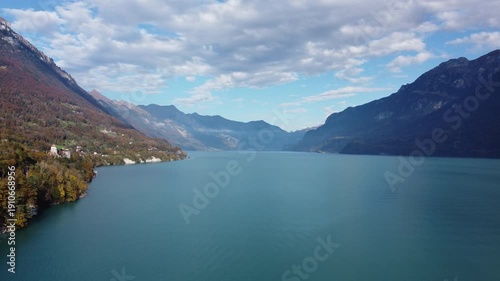 Wallpaper Mural Breathtaking drone view over the emerald waters of Lake Brienz in the Swiss Alps. Dramatic mountain slopes and lush forests frame the pristine lake under a bright, cloudy sky. Cinematic travel scene. Torontodigital.ca