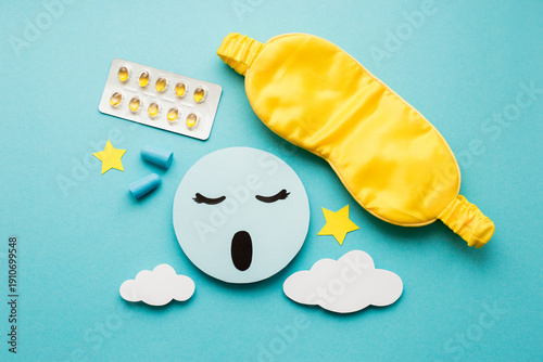 Healthy sleep creative concept. Sleep mask, vitamin D tablets in a blister pack, clouds, stars, earplugs on blue background