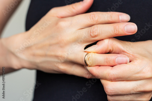 Foto Woman struggles to remove a ring stuck on her finger, showing tension and effort in her hands moment in close-up detail